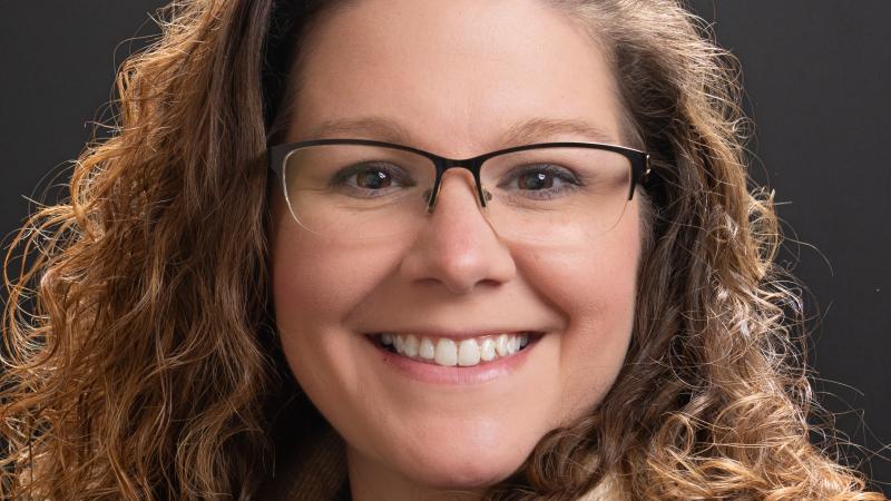 woman with brown curly hair wearing glasses