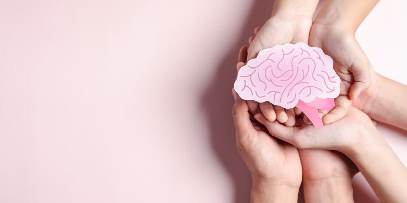 Hands coming together holding a paper image of a brain