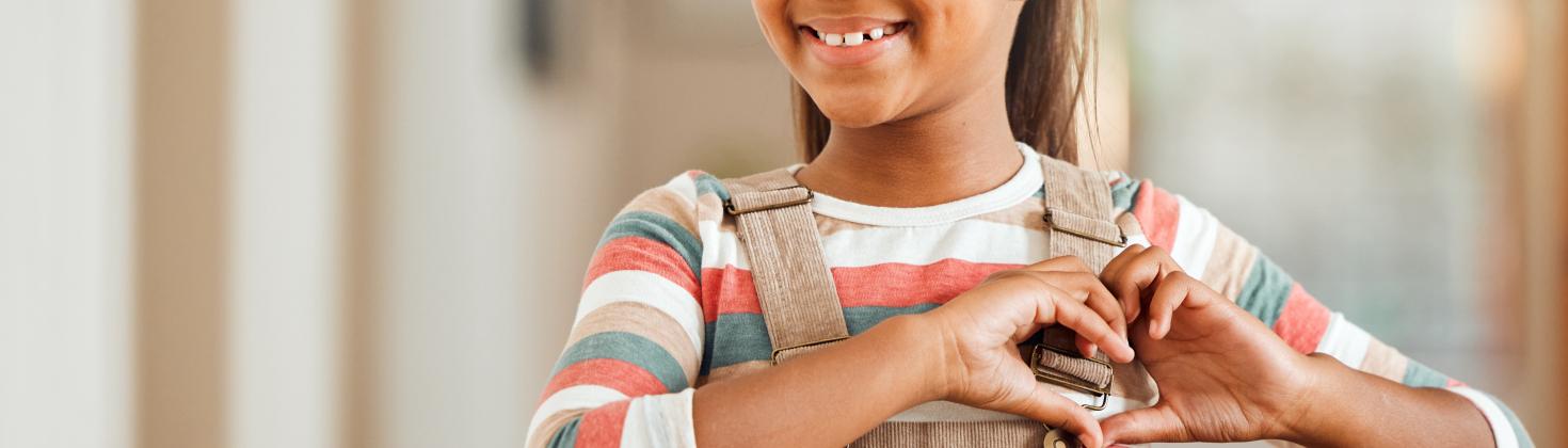 Young girl of color happy displaying a heart with her hands