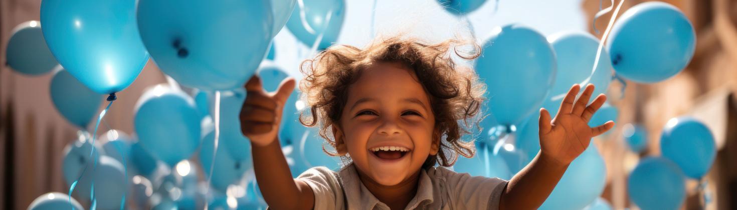 Young happy boy running with balloons around him