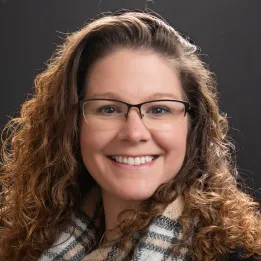 woman with brown curly hair wearing glasses