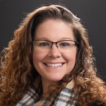 woman with brown curly hair wearing glasses